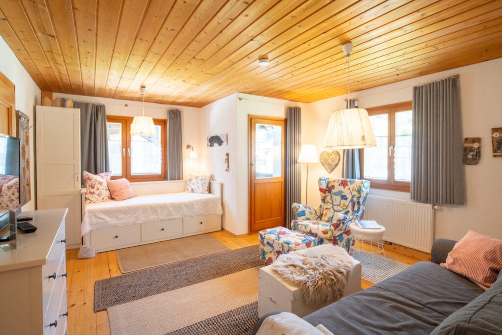 Gemütliches Wohnzimmer im Haus Berta, Montafon, mit Holzdecke, bequemen Sitzgelegenheiten und vielen.